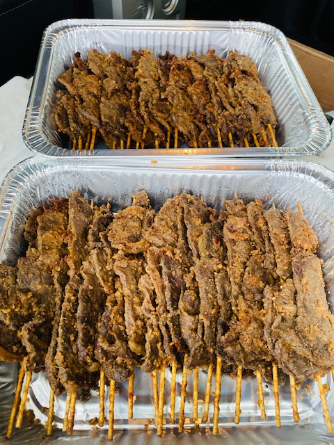 Two trays of well-cooked meat skewers with visible grill marks